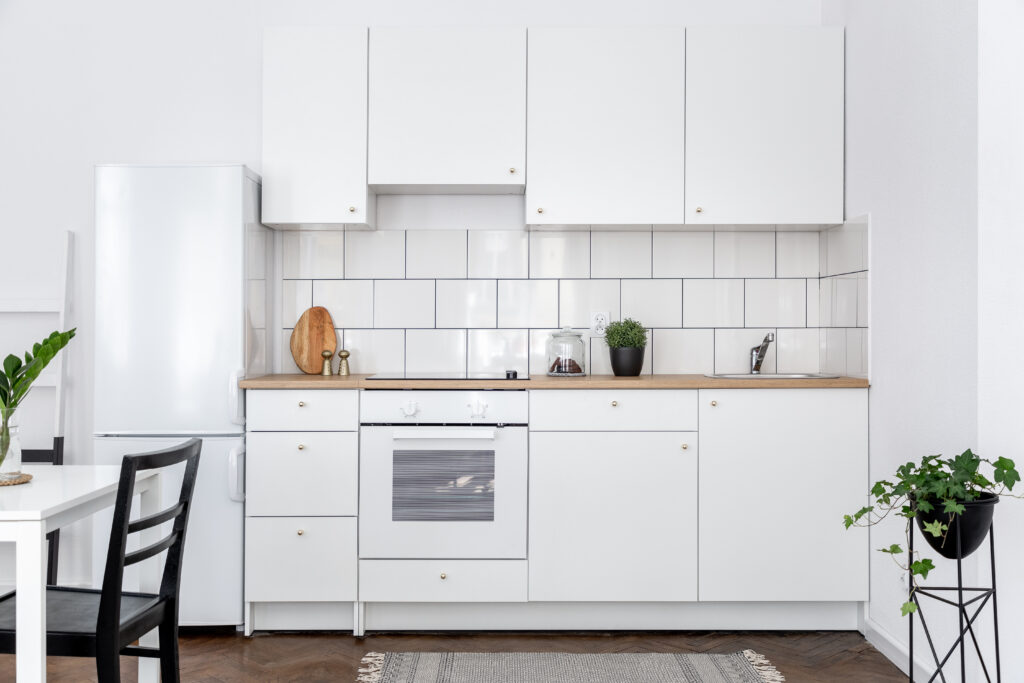 Contemporary kitchen with white cupboards and dining table with black chairs