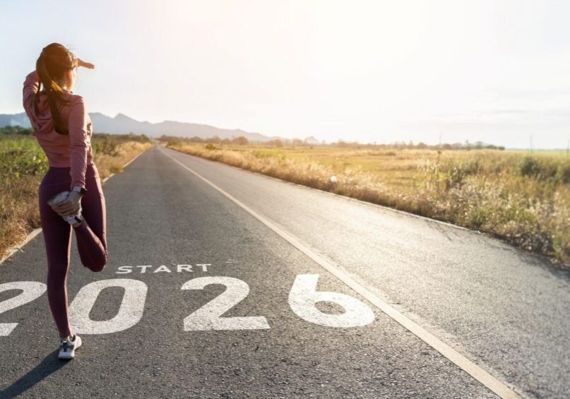 Ed Neir Construction wishes all a Happy New Year - a woman in workout clothes is stretching & looking in the distance, ready to start 2026.